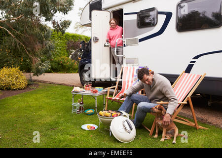 Couple In Van Enjoying Barbeque On Camping Holiday Stock Photo