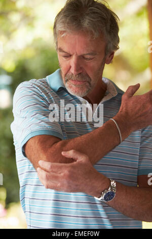 Mature Man Suffering From Painful Elbow At Home Stock Photo