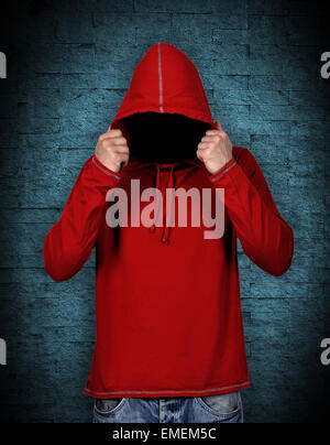 man in hoodie without a face on blue wall background Stock Photo