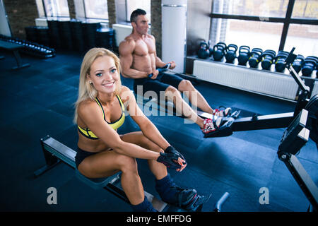 Muscular man and sporty woman doing exercises on training simulator in crossfit gym Stock Photo