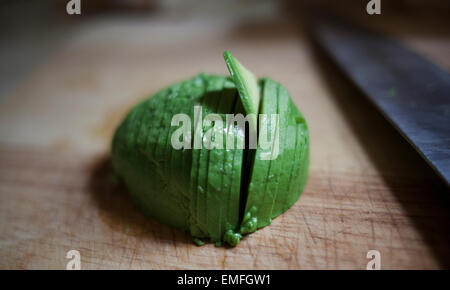 https://l450v.alamy.com/450v/emfgw1/thinly-cut-avocado-on-cutting-board-with-knife-emfgw1.jpg