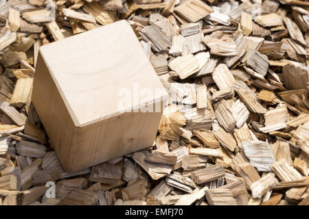 Wooden cube lying in the garden on background of light mulch viewed from above Stock Photo