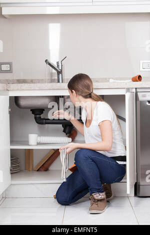 Woman plumber fixing the kitchen Stock Photo