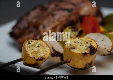 Charred vegetable kabobs with grilled pork in background Stock Photo