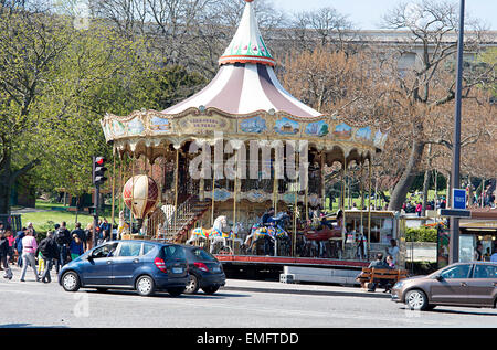 Tourists visit a park and Merry-go-round across the River Seine from the Eiffel Tower in Paris. Stock Photo