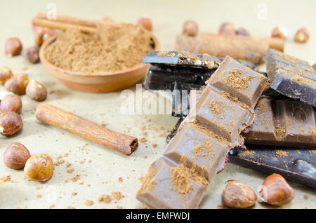 Bunch of chocolate sticks, cinnamon and hazelnuts on a table Stock Photo