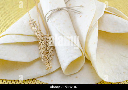 Bunch of tortillas and a stick of wheat on a yellow tablecloth Stock Photo