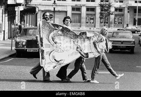 Comedy actor John Cleese with Not The Nine O Clock News' cast members Rowan Atkinson and Pamela Stephenson carry a cardborad cut out with the help of 3ft 10 in actor David Rappaport as they take their new show 'The Secret Policeman's Other Ball' on the road. 6th September 1981. Stock Photo