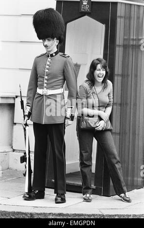 A guardsman standing outside Clarence House, the residence of the Queen Mother, is put to the test by some humour from an American tourist. 27th July 1981. Stock Photo