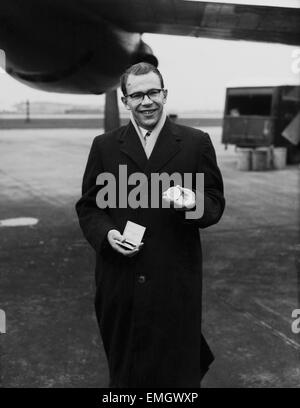 British athlete Chris Brasher shows off his gold medal which he won at the 1956 Olympic Games in Melbourne, on his arrival back in London. 10th January 1957. Stock Photo