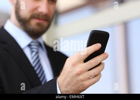 Executive hand using a smartphone in the street with an office building in the background Stock Photo