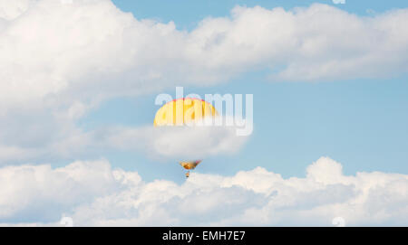 Yellow hot air balloon flying through white clouds. Conceptual image of freedom, making a journey or going up. Stock Photo