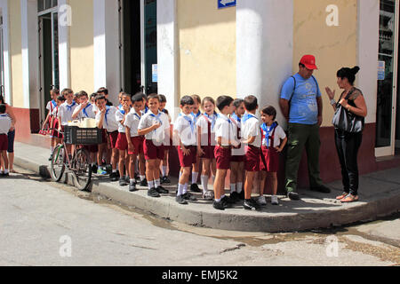 Young school children in school uniforms wait to cross street in Trinidad Cuba Stock Photo