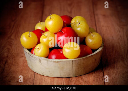 yellow and red plums in bowl on wooden table Stock Photo
