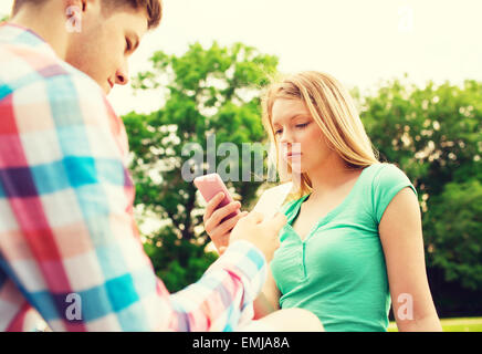 couple with smartphones in park Stock Photo