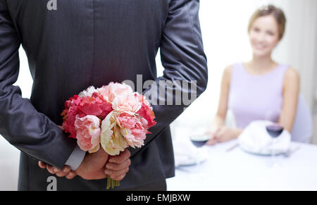 close up of man hiding flowers behind from woman Stock Photo