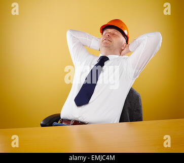 Male engineer in office, he wearing a white shirt and tie, head he wears a orange hard hat Stock Photo