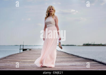 Standing woman wearing an evening gown of pink moire with