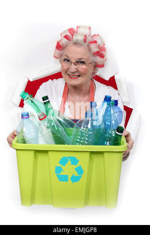 granny with hair curlers holding recycling tub full of plastic bottles Stock Photo
