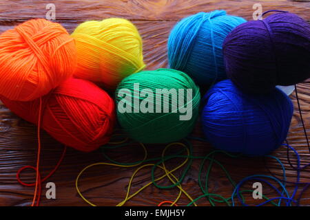 on a wooden board are colored balls of threads for knitting Stock Photo