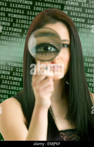Woman looking through a loupe at a computer virus concept Stock Photo