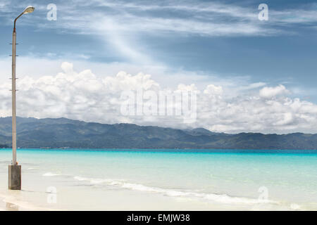 Lighter on withe and beach near deep blue sea with big white clouds on blue sky Stock Photo