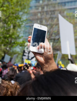 Man taking photo with iPhone above a crowd at a protest rally - USA Stock Photo