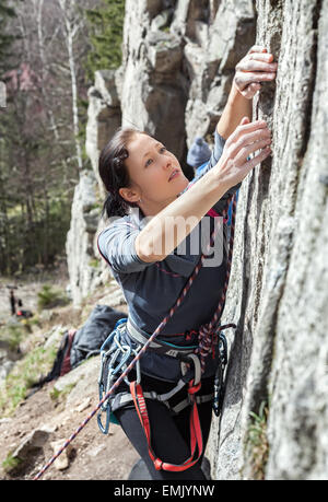 Portrait of a beautiful young woman climbing difficult wall. Stock Photo
