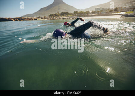 Triathlon swimmers churning up the water. Athletes practicing for triathletic race in lake. Stock Photo