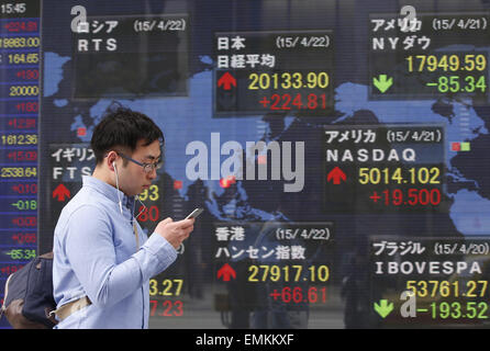 Tokyo, Japan. 22nd Apr, 2015. A man walks past an electronic board showing the stock index in Tokyo, Japan, on April 22, 2015. The 225-issue Nikkei index jumped 224.81 points, or 1.13 percent, from Tuesday at 20,133.90, the highest close since April 2000. © Stringer/Xinhua/Alamy Live News Stock Photo