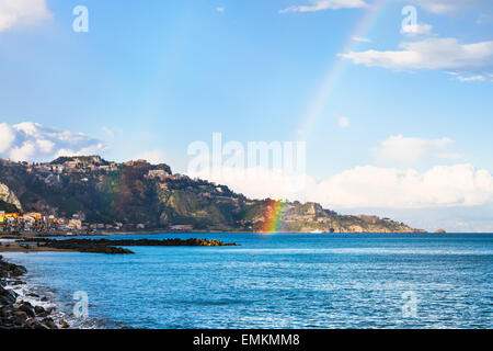 view of Giardini Naxos resort, Taormina cape and rainbow in Ionian Sea in spring, Sicily Stock Photo