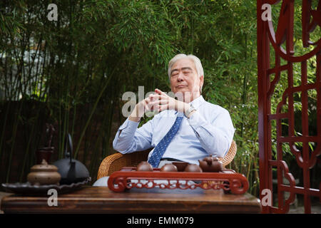 An old man sat in the yard with closed eyes Stock Photo