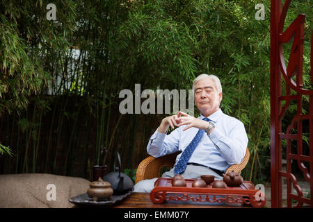 An old man sat in the yard with closed eyes Stock Photo