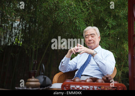 An old man sat in the yard with closed eyes Stock Photo