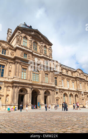 Paris, France - August 09, 2014: Inner courtyard and facade of The Louvre Museum with walking tourists in a summer day Stock Photo