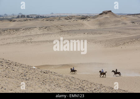 Horses and horsemen in the desert beside the Pyramids of Giza, in Giza, near Cairo, Egypt, Africa. Stock Photo
