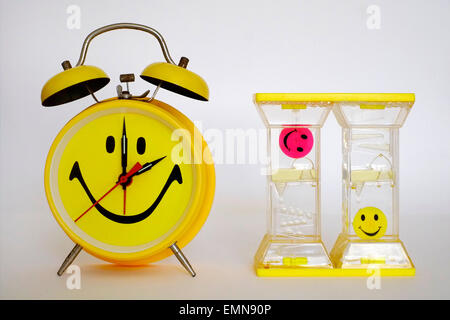 bright yellow traditional alarm clock with smiley face alongside oil driven timer Stock Photo