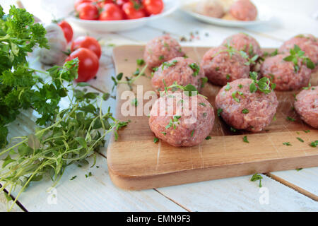 Raw meat balls with herbs on wooden board Stock Photo