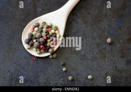 Mixture of different peppercorns in a wooden spoon top view Stock Photo