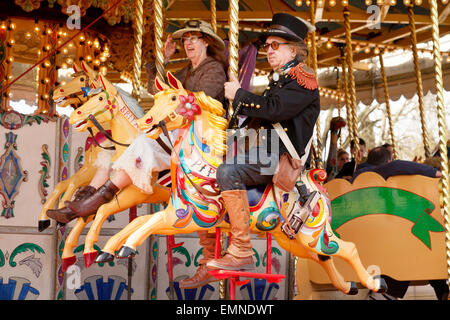 Middle aged caucasian couple having fun on a roundabout or carousel, Norfolk, UK Stock Photo