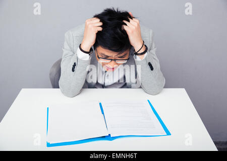 Worried businessman sitting at the table and reading papers in office Stock Photo