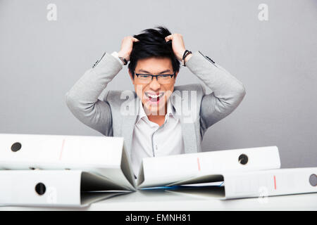 Depressed asian businessman in glasses sitting at the table with folders and touching her hair Stock Photo
