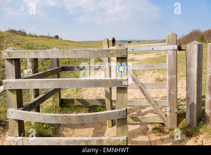 Sign on kissing gate on Wales Coast Path with distant walker in Oxwich National Nature Reserve on Gower Peninsula, Swansea, Wales, UK, Britain Stock Photo