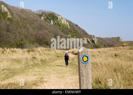Footpath sign with walker on Wales Coast Path in Oxwich National Nature Reserve on Gower Peninsula Swansea Wales UK Britain Stock Photo