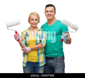 smiling couple in gloves with paint rollers Stock Photo