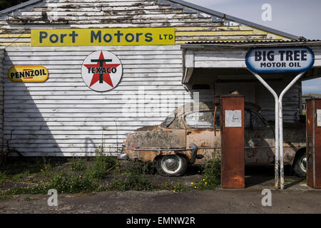 Old abandoned petrol station with a Plymouth Belvedere 1950s car, and two petrol pumps,  rotting on the forecourt. Ormondville, Stock Photo