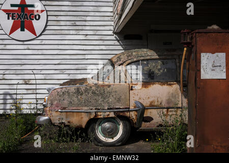 Old abandoned petrol station with a Plymouth Belvedere 1950s car, and two petrol pumps,  rotting on the forecourt. Ormondville, Stock Photo