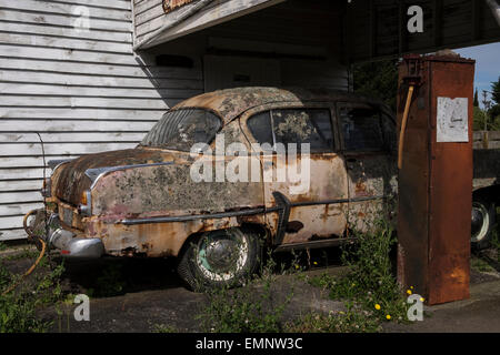 Old abandoned petrol station with a Plymouth Belvedere 1950s car, and two petrol pumps,  rotting on the forecourt. Ormondville, Stock Photo