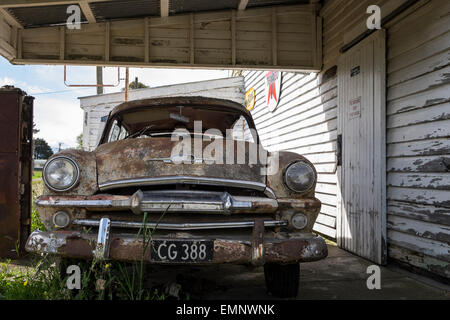 Old abandoned petrol station with a Plymouth Belvedere 1950s car, and two petrol pumps,  rotting on the forecourt. Ormondville, Stock Photo