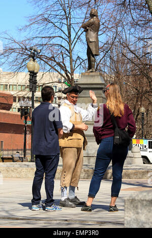 Boston Massachusetts Freedom Trail tour guide in period costume talks with tourists in near Sam, Samuel Adams statue landmark. Stock Photo